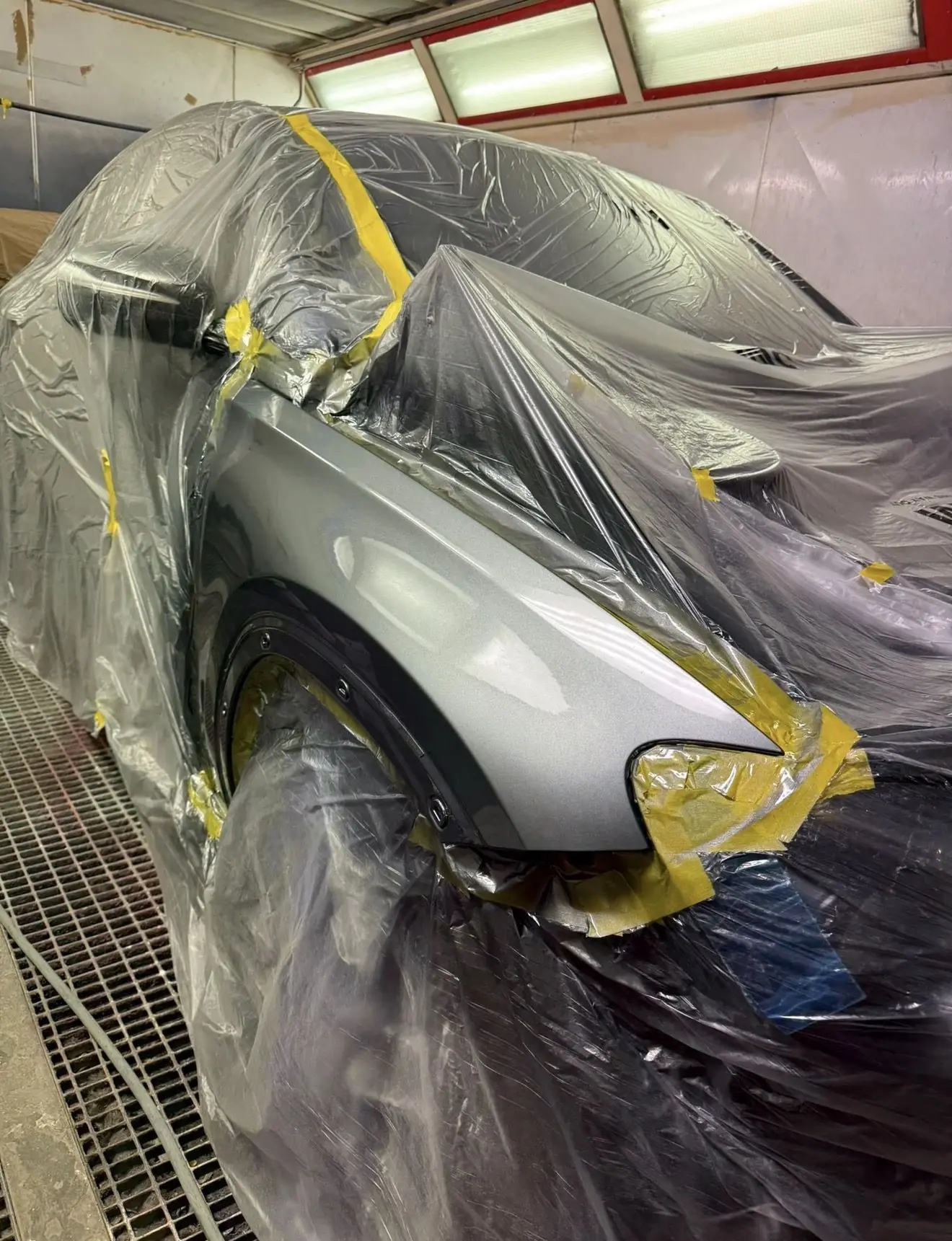 A car masked up in the spray booth with a freshly painted wing at White Rose Motors