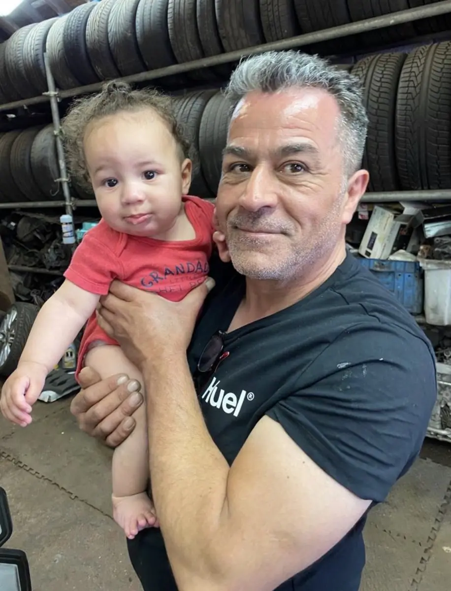 A White Rose Motors grandad holding his grandson in the workshop