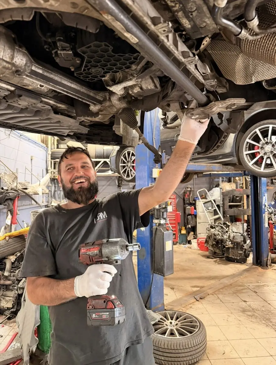 A White Rose Motors mechanic working under a car on the ramp